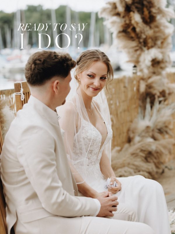Brautpaar sitzt l&auml;chelnd bei der Hochzeit in der Strandperle D&uuml;sseldorf.